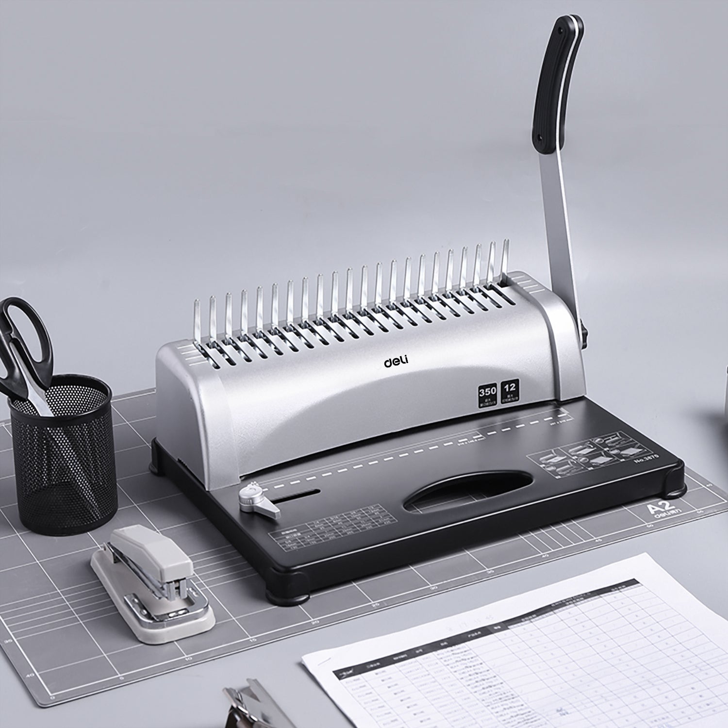 Comb binding machine on a desk with office supplies Deli E3870 Comb Binding Machine