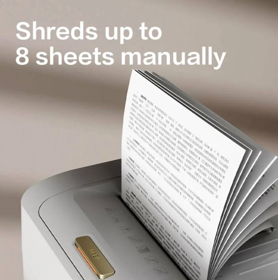 A close-up of a document shredder in action, with a page of text fed into the open top slot. Large white text at the top reads 'Shreds up to 8 sheets manually' against a soft beige background.