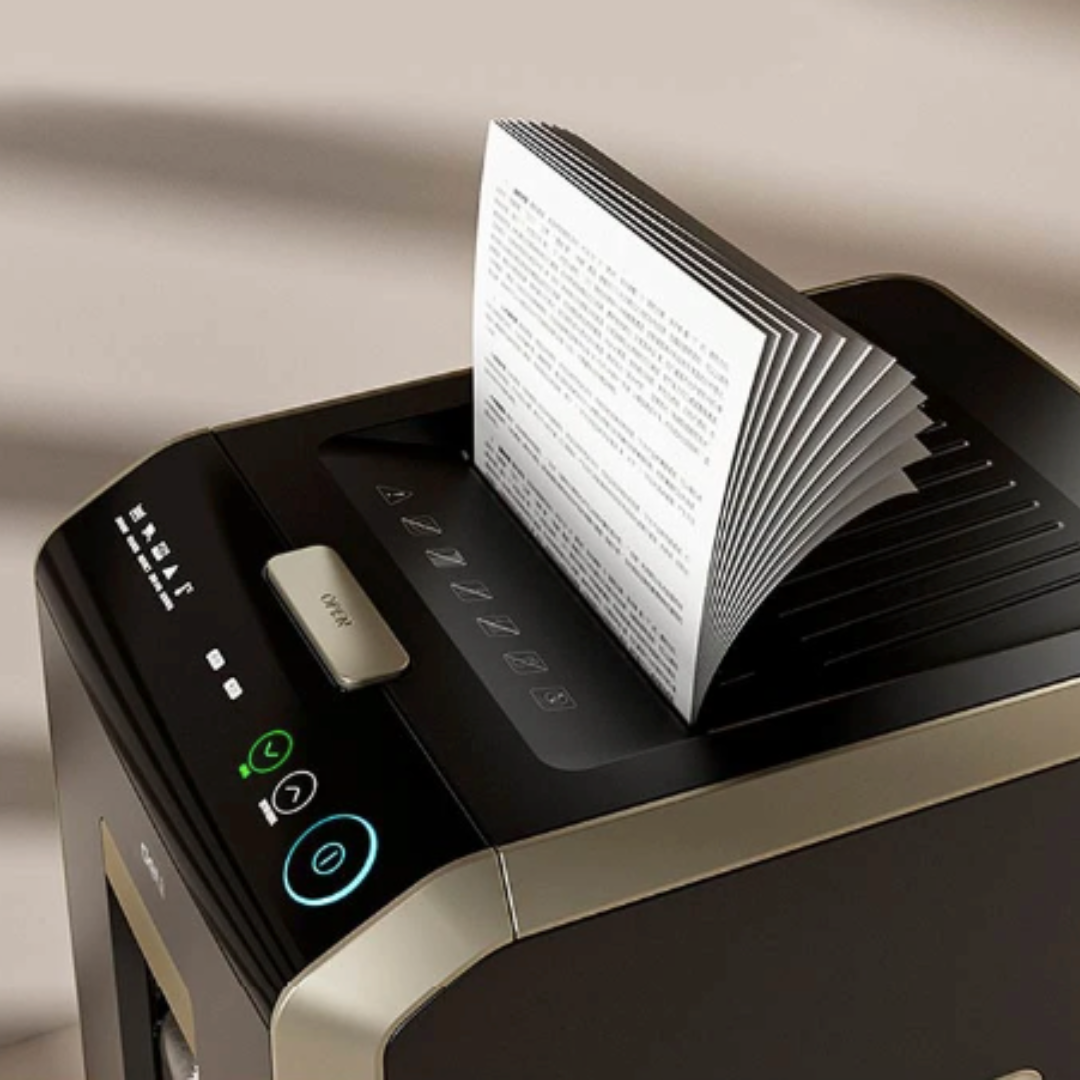Paper being shredded by a black and silver paper shredder on a beige background Deli T080 Auto-Feed Paper Shredder (20L)