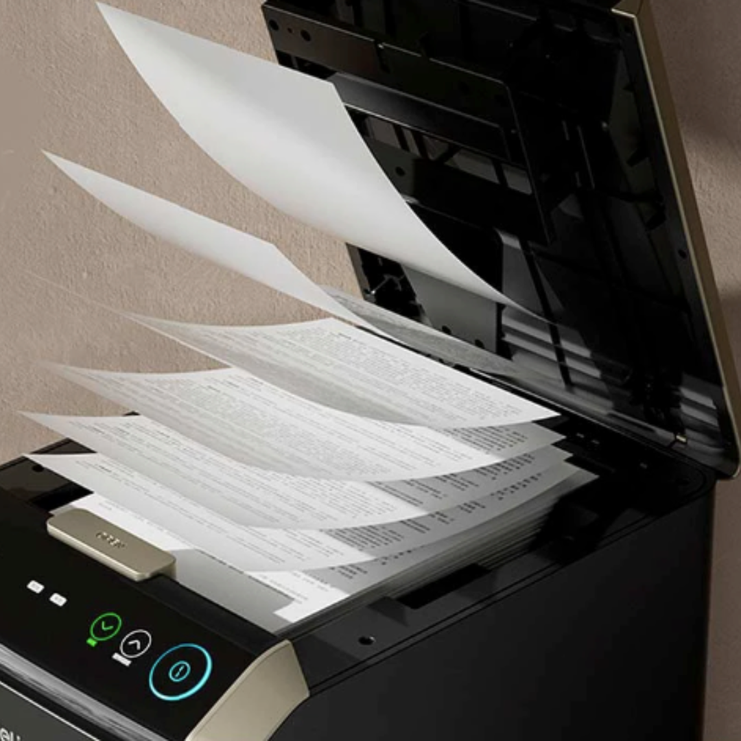 Black printer with paper being fed into it against a beige wall. Deli T090 Auto-feed Paper Shredder (18L)